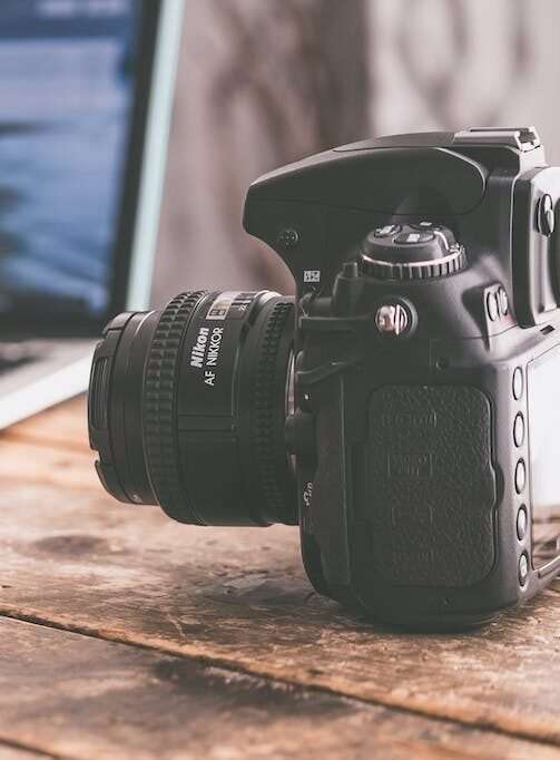 Black Dslr Camera on Beige Wooden Surface